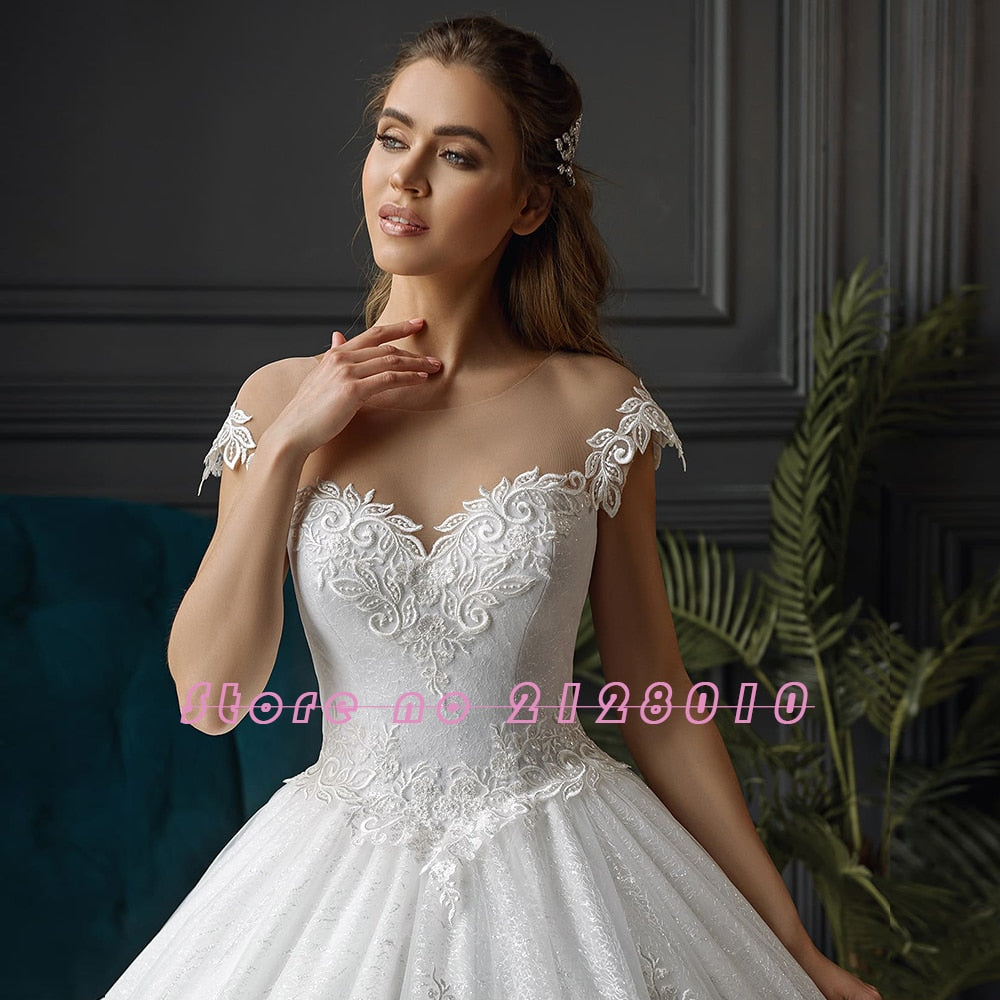 Close-up view of a bride showcasing the intricate lace bodice and delicate off-the-shoulder neckline of a shiny ball gown wedding dress.