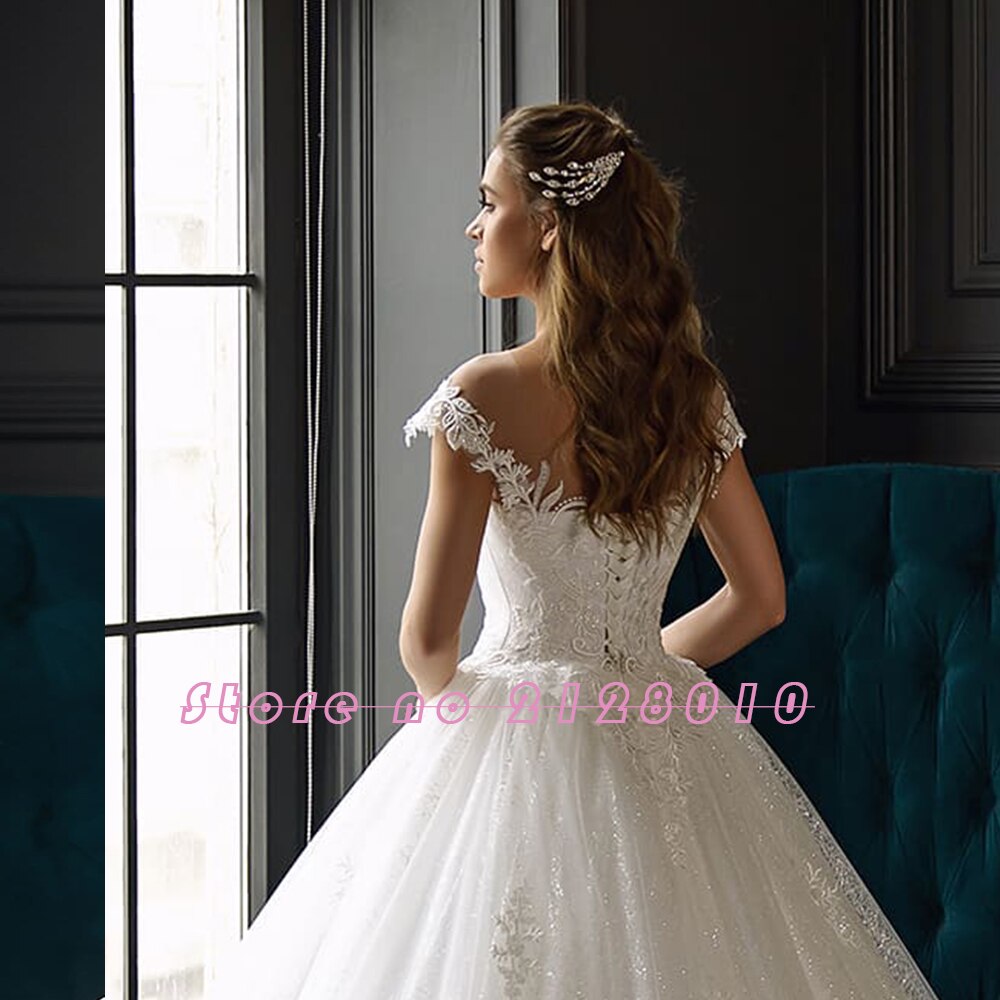 Profile view of a bride with elegant hair accessories, wearing a detailed off-the-shoulder lace ball gown wedding dress.