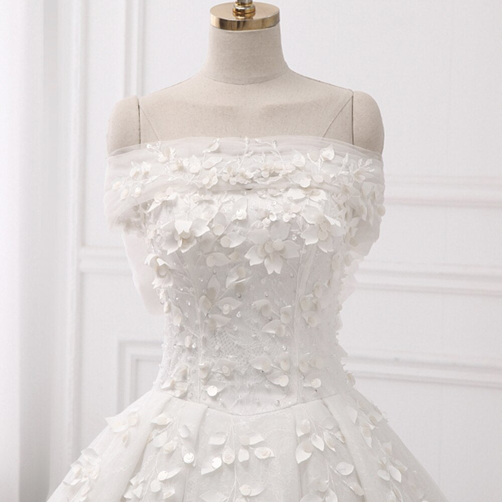 Close-up of the bodice on a princess ball gown wedding dress with off-the-shoulder sleeves and delicate floral lace appliques.
