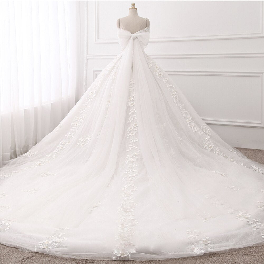 Elegant back view of a princess ball gown wedding dress with a dramatic tulle bow and lace-up corset closure.