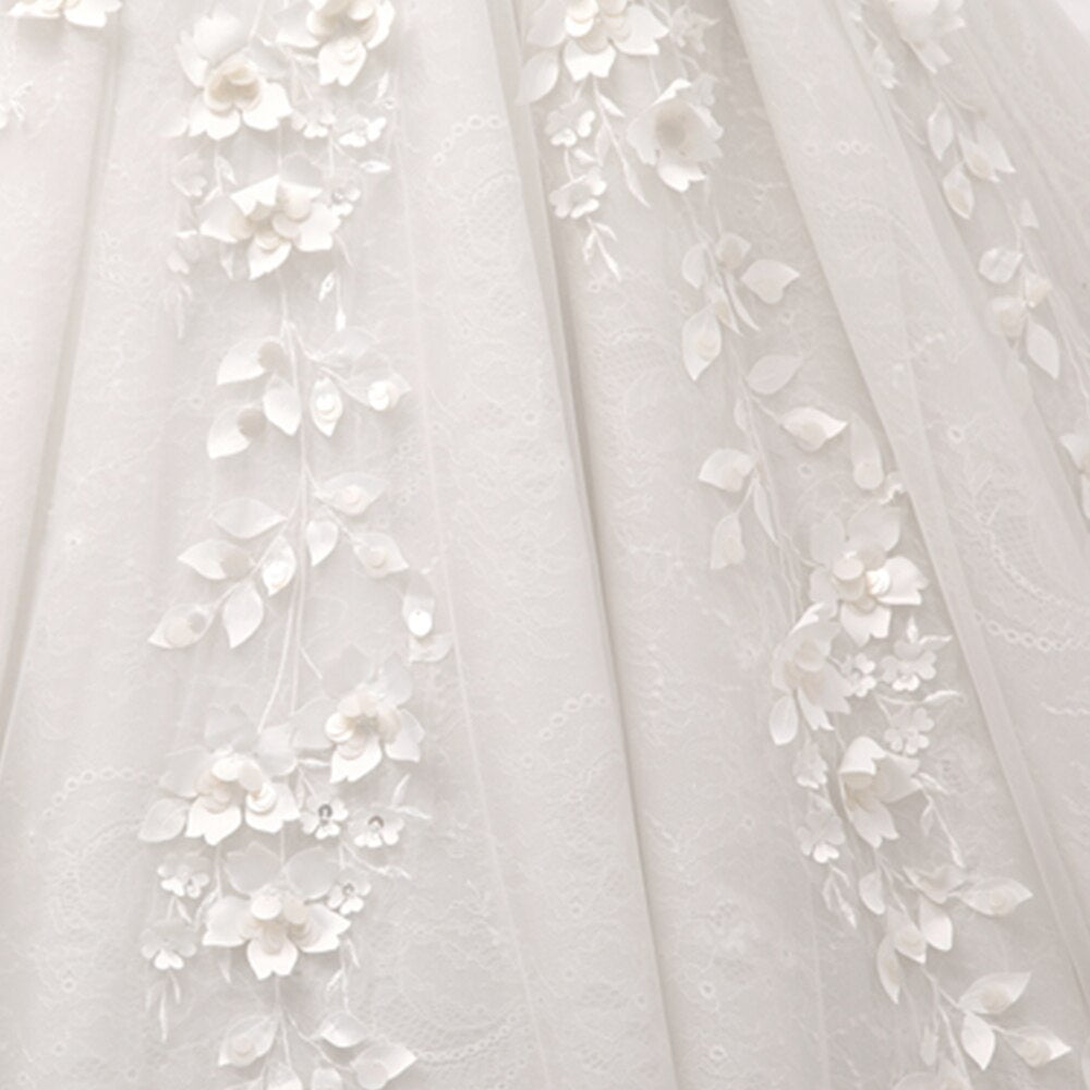 Close-up detail of the intricate three-dimensional floral lace and sequin embellishments on a princess wedding gown
