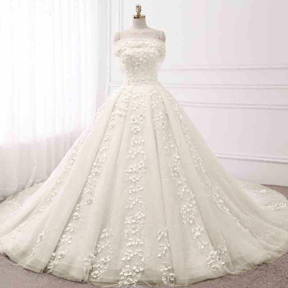 Mannequin display of a princess ball gown wedding dress, focusing on the off-the-shoulder neckline and ornate floral lace embroidery.