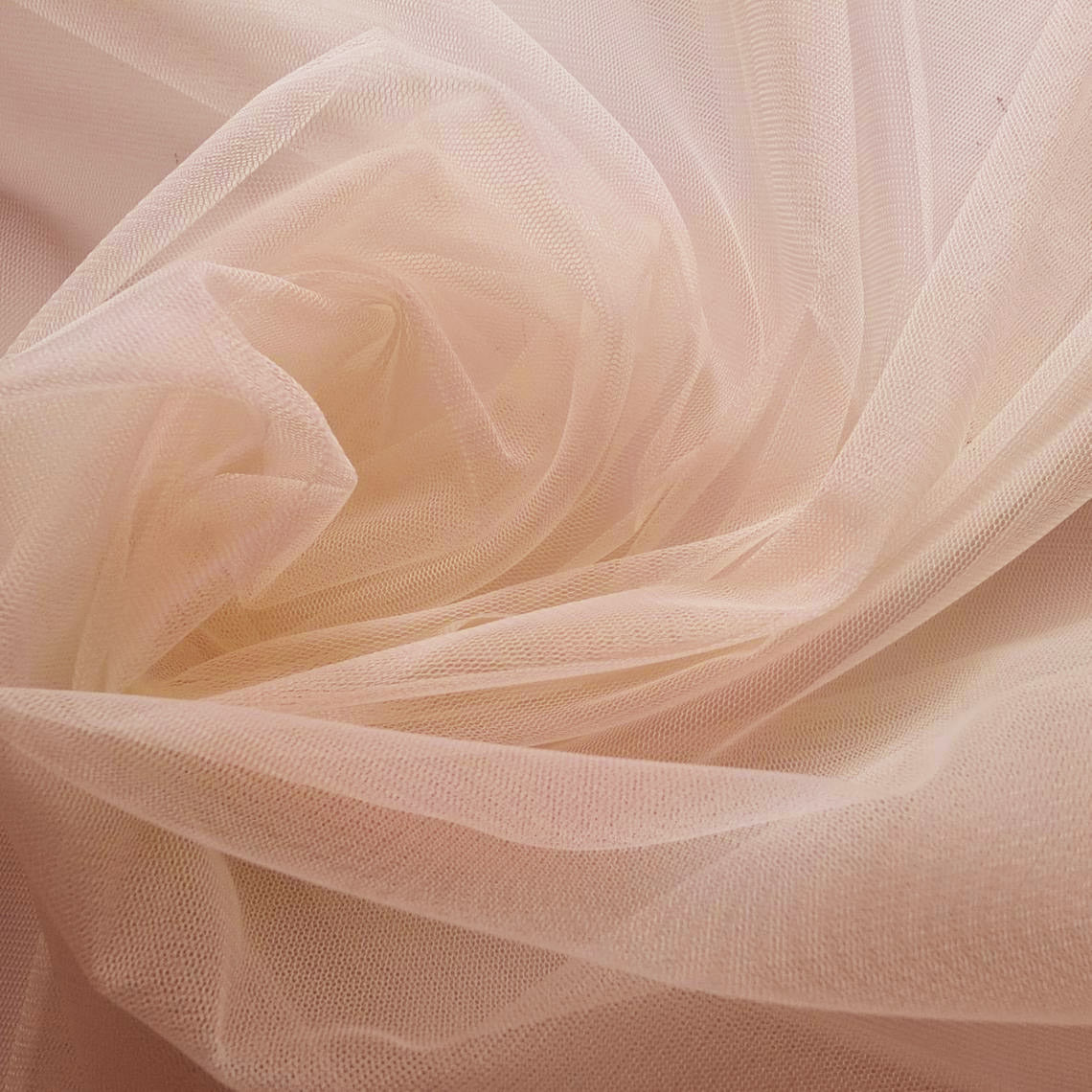 A detailed close-up shot of soft, beige-toned tulle fabric, perfect for romantic bridal gowns or veils.