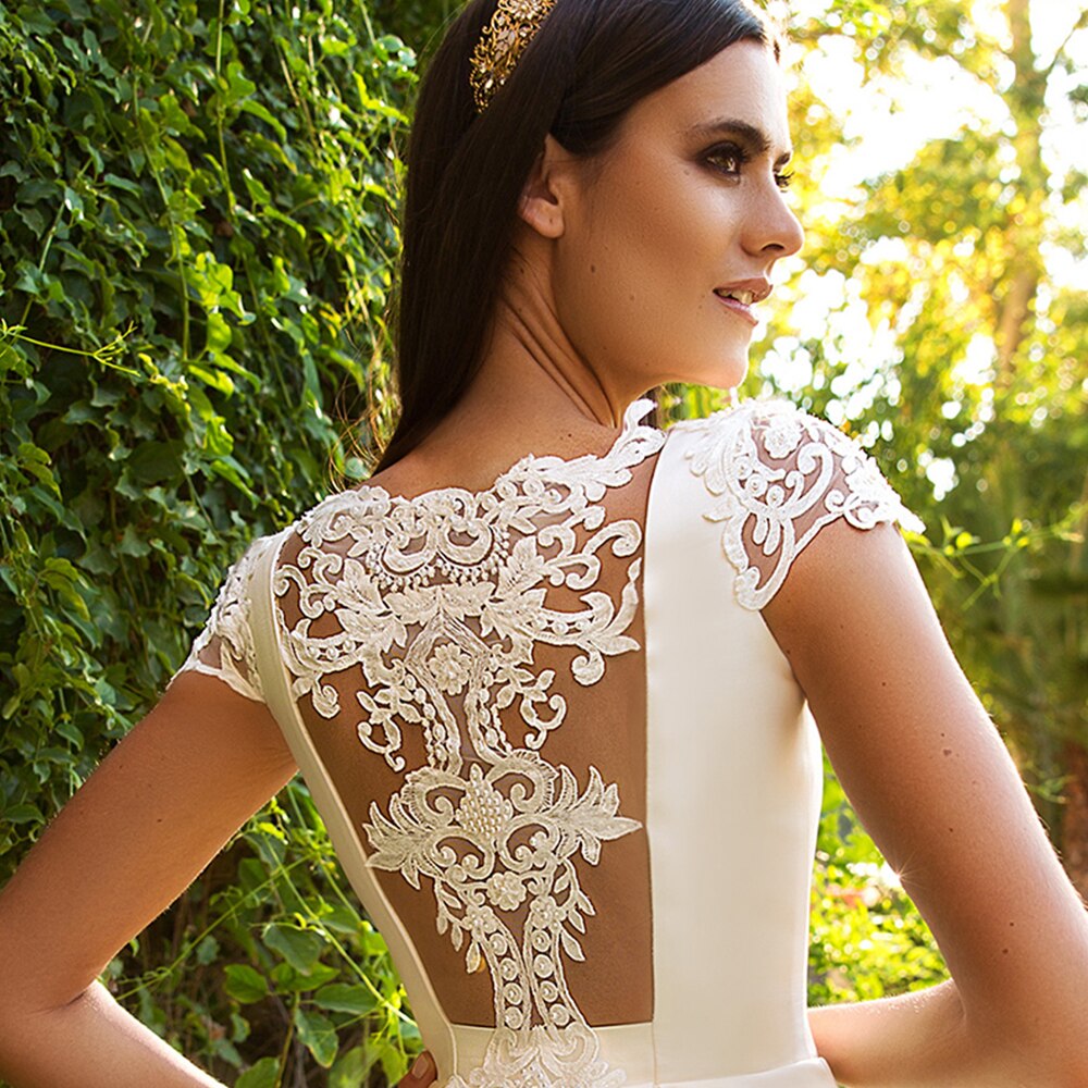 Close-up of the bodice on a princess ball gown wedding dress with off-the-shoulder sleeves and delicate floral lace appliques.