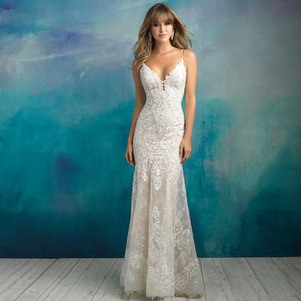 Full-length view of a bride wearing a form-fitting mermaid wedding dress with spaghetti straps, intricate beading, and floral lace applique.