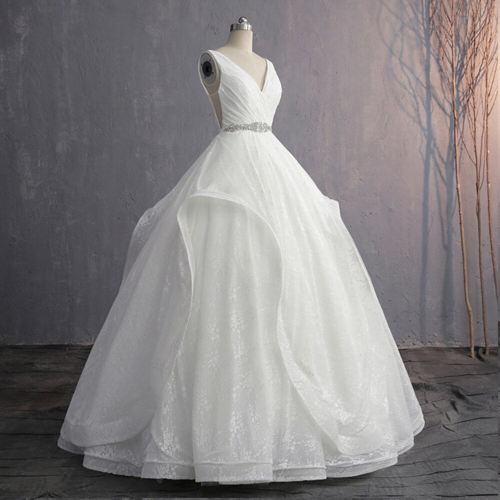 Side-profile view of an elegant V-neck bridal gown on a dress form, highlighting the flowing silhouette and lace-up back design.