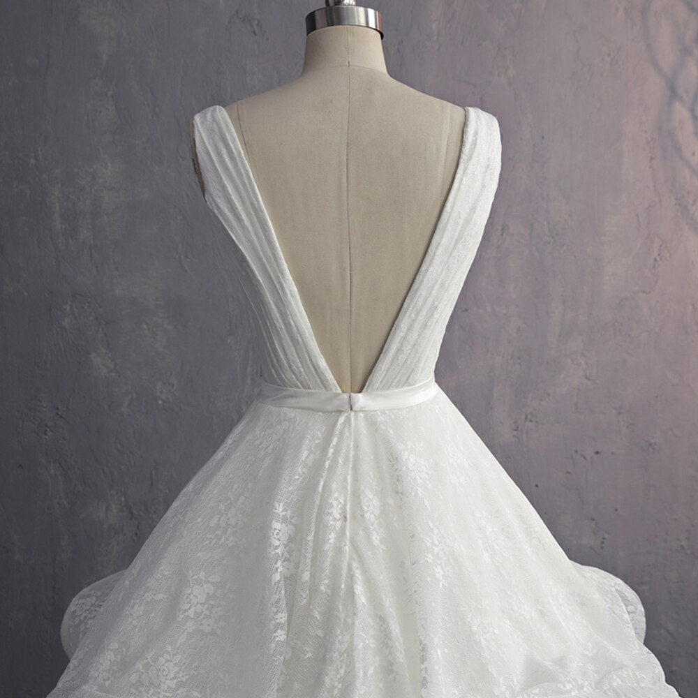 Rear view of an ivory bridal gown displayed on a mannequin, featuring a deep V-neck and a lace-up corset back.